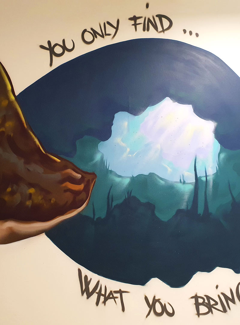 Graffiti vægmaleri der forestiller en rokke der svømmer i vandet ind i en grotte